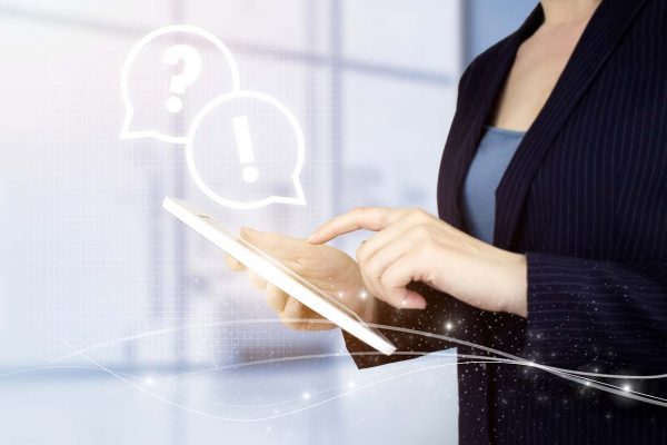 FAQ frequently asked questions concept. Hand touch white tablet with digital hologram question mark sign on light blurred background. Business support concept. Problems and solutions